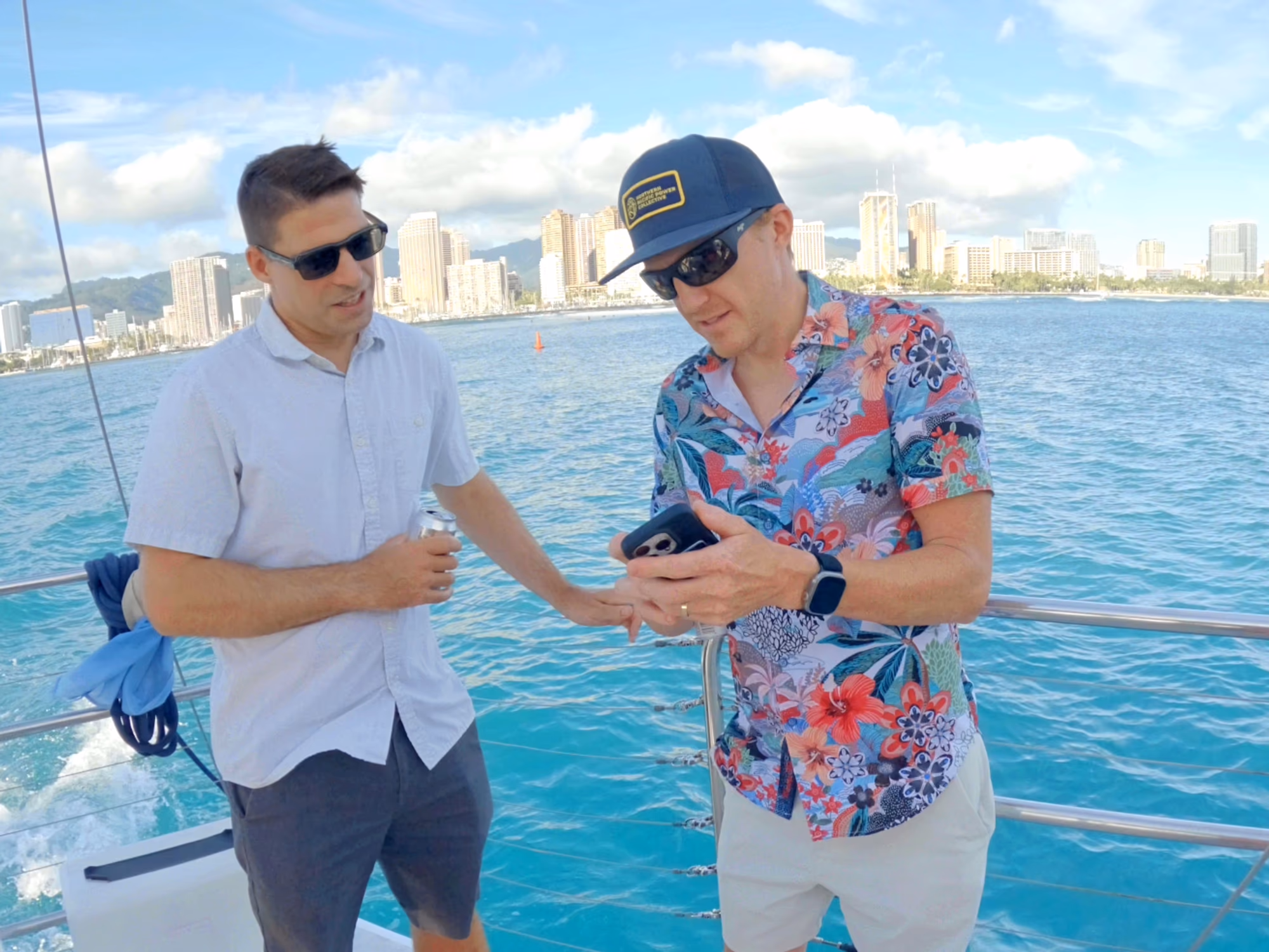Two men on a boat with Honolulu skyline and ocean