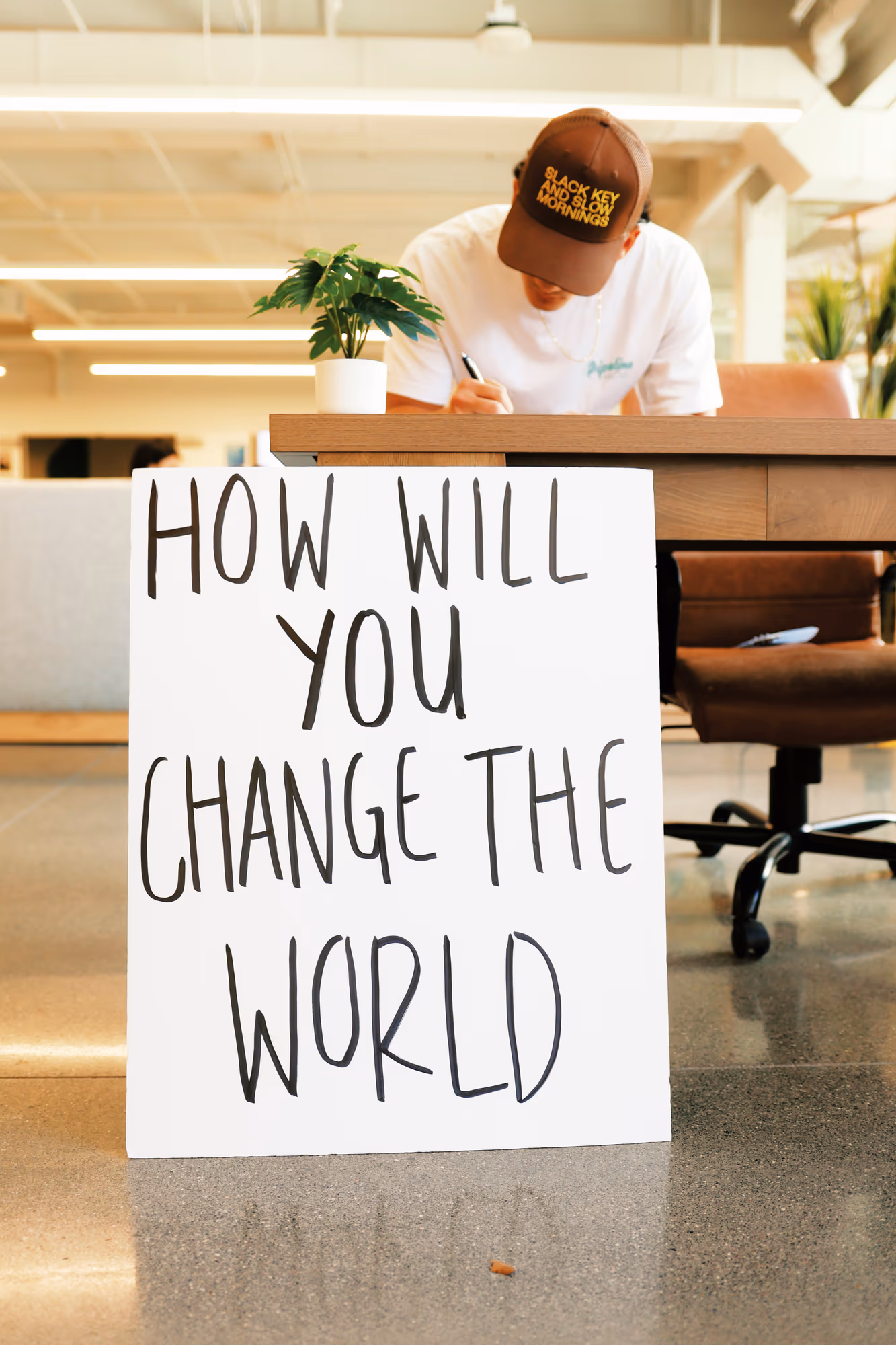 A participant writes behind a sign asking How will you change the world at Built for This.