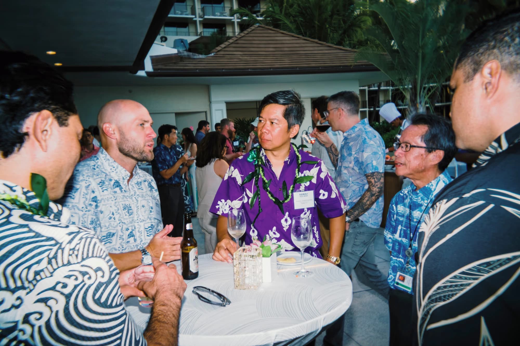 A group in conversation around a high table on an outdoor terrace.
