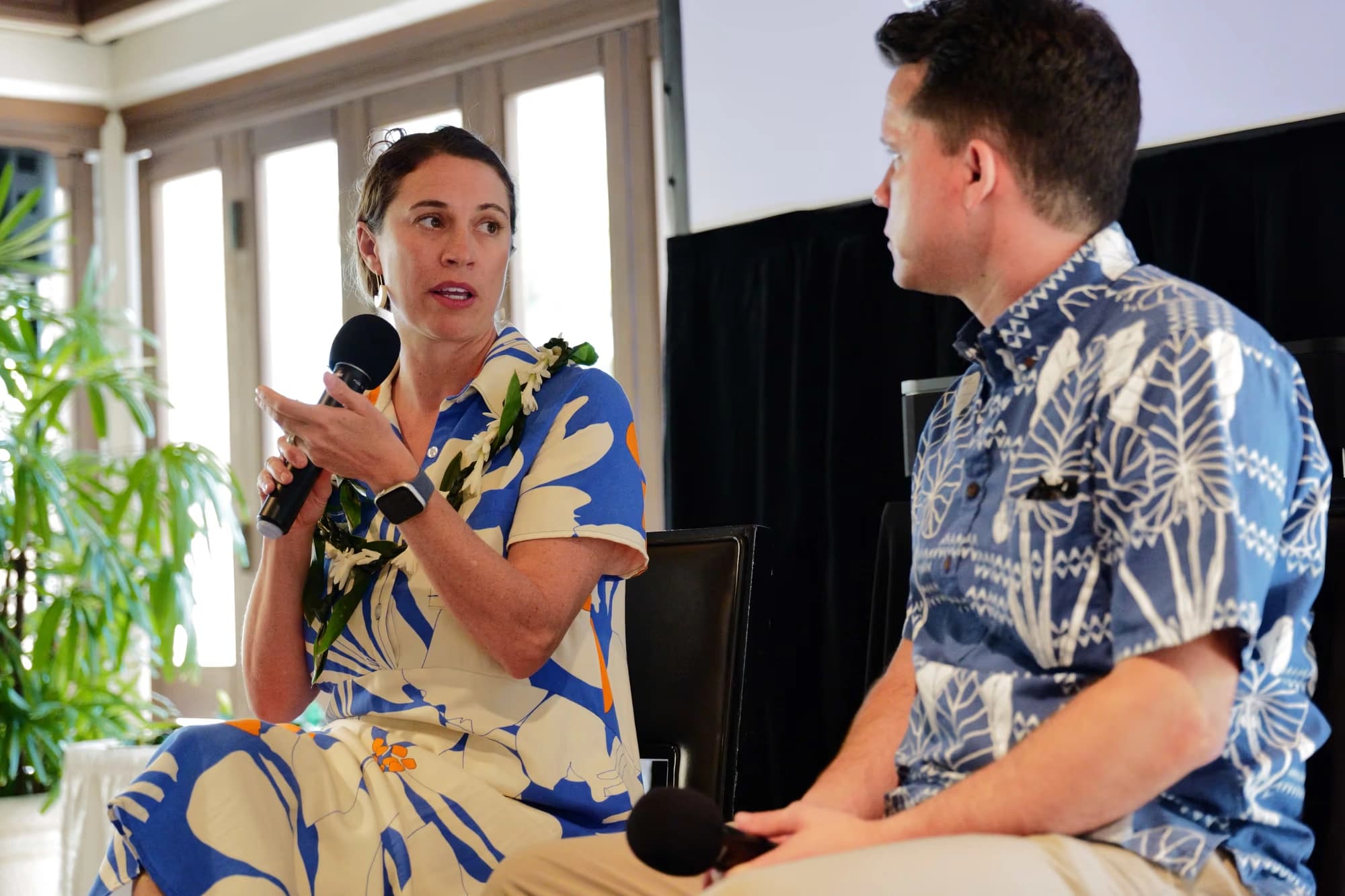 Two seated speakers holding microphones during an Executive Forum conversation.