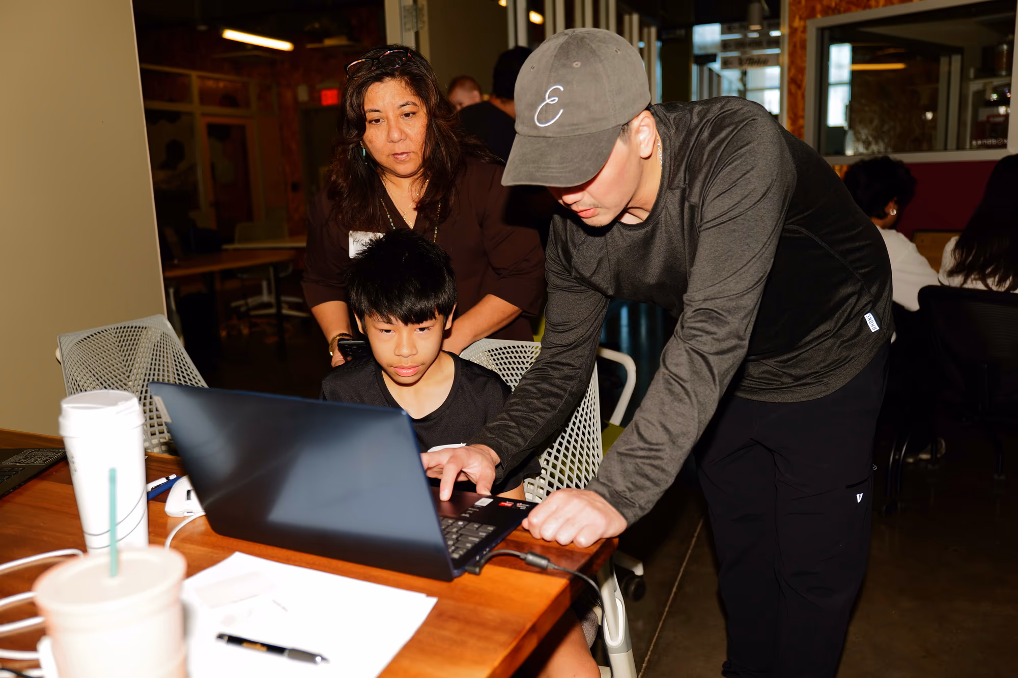 Three people working together around a laptop during Build with Grok Bot.