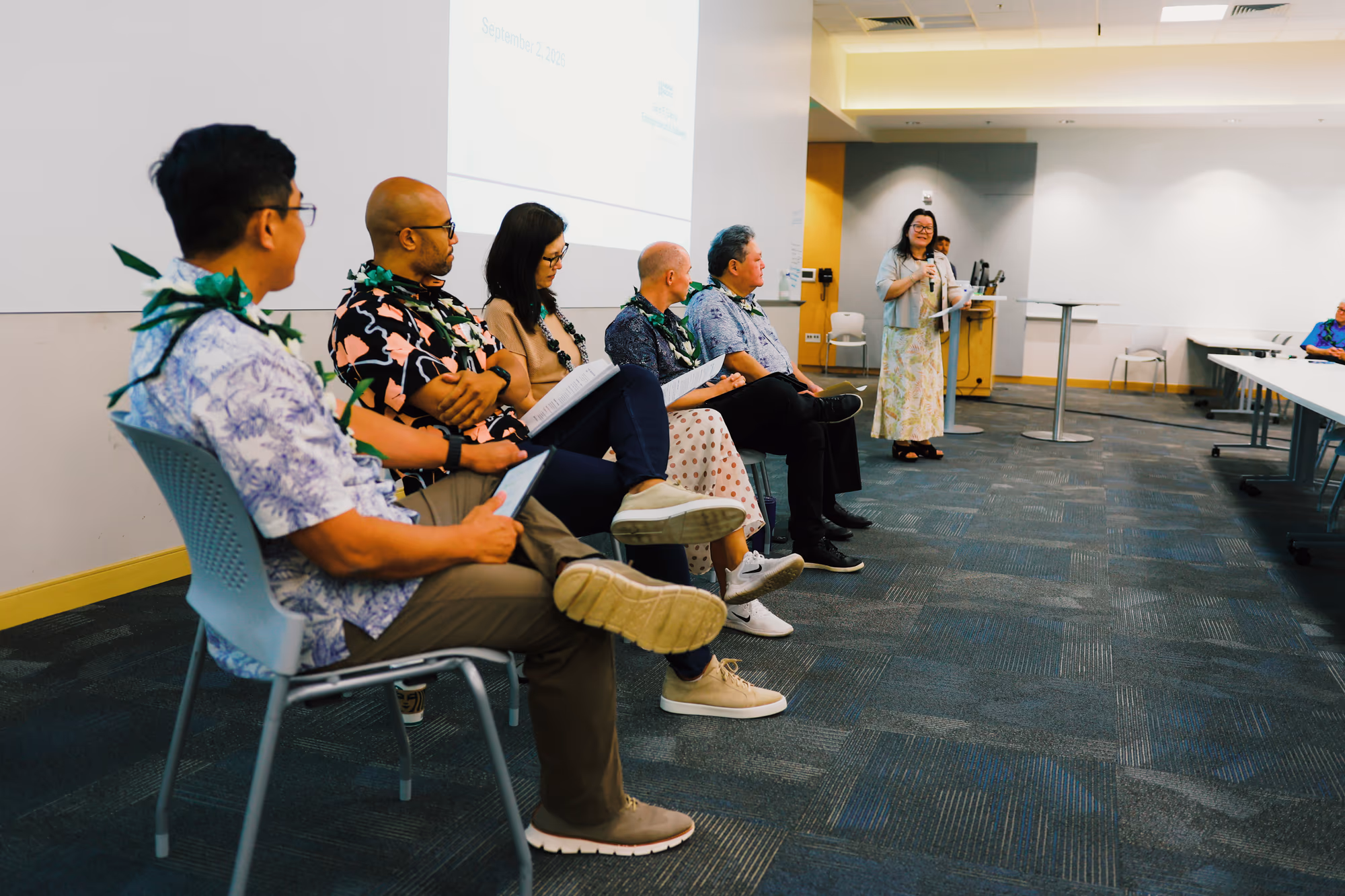 A seated panel listens while a speaker addresses the room at Hawaii Pacific University.
